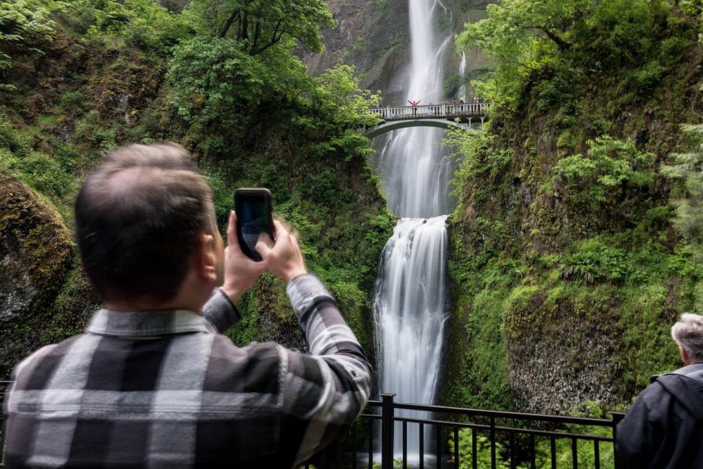 Man taking photo of Multnomah Falls