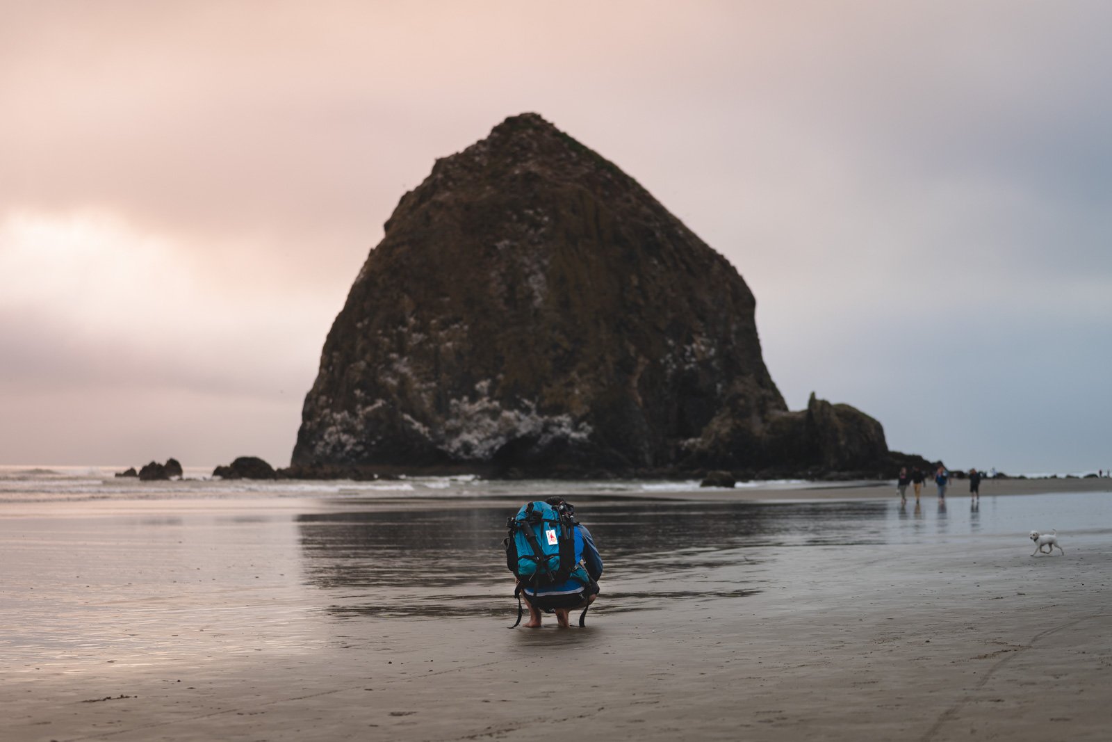 Garrett bending down for a photo in front of Haystack rock.