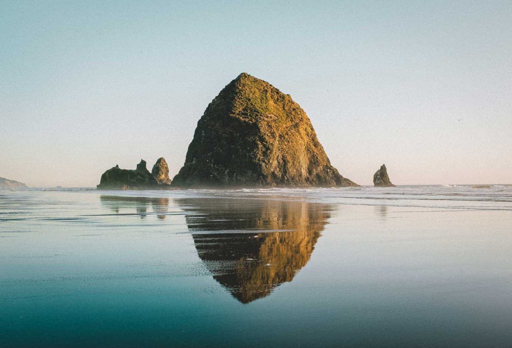 Haystack Rock and reflection at Cannon Beach at sunset.