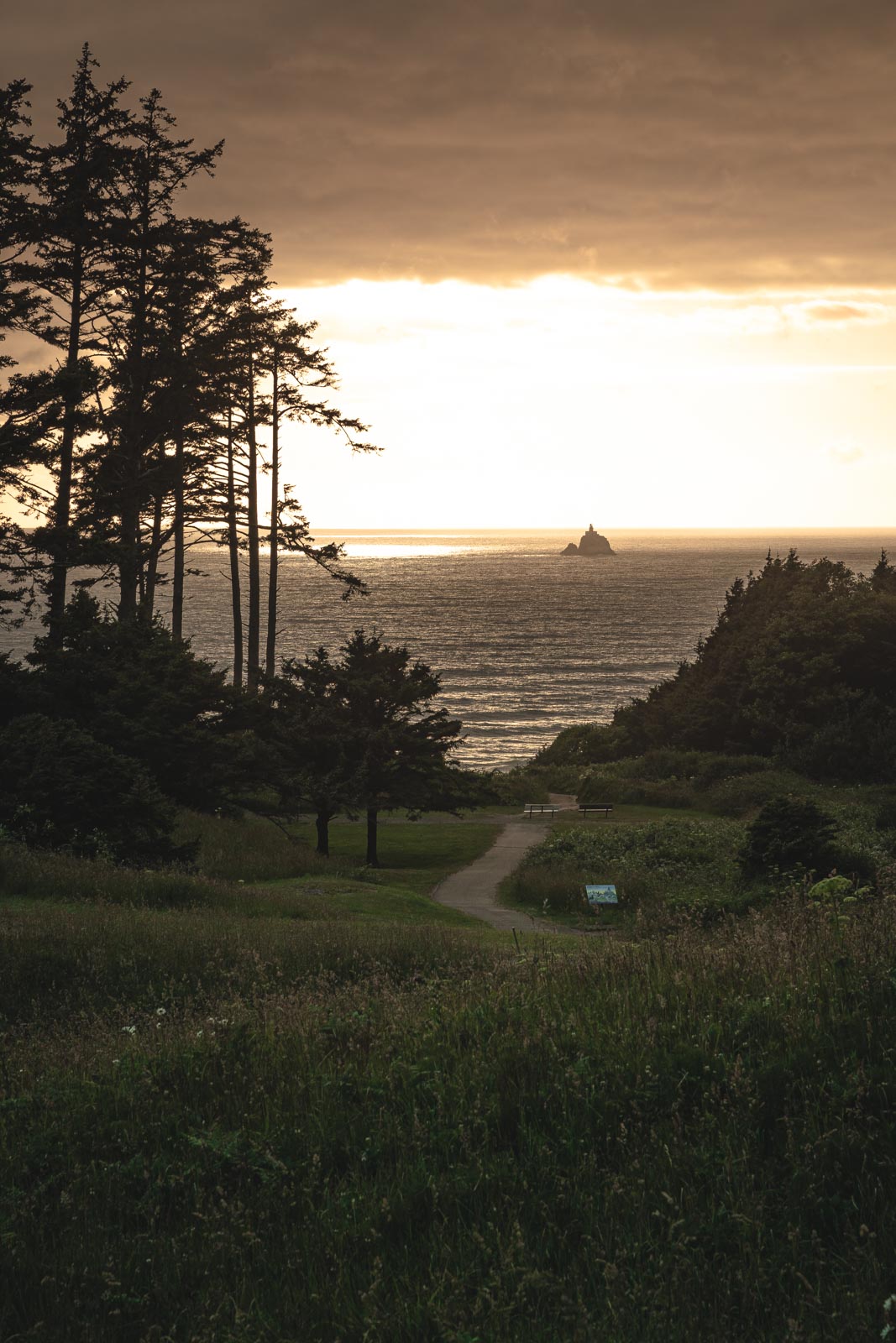 Ecola State Park Trail leading to Tillamook lighthouse in the distance in the ocean.