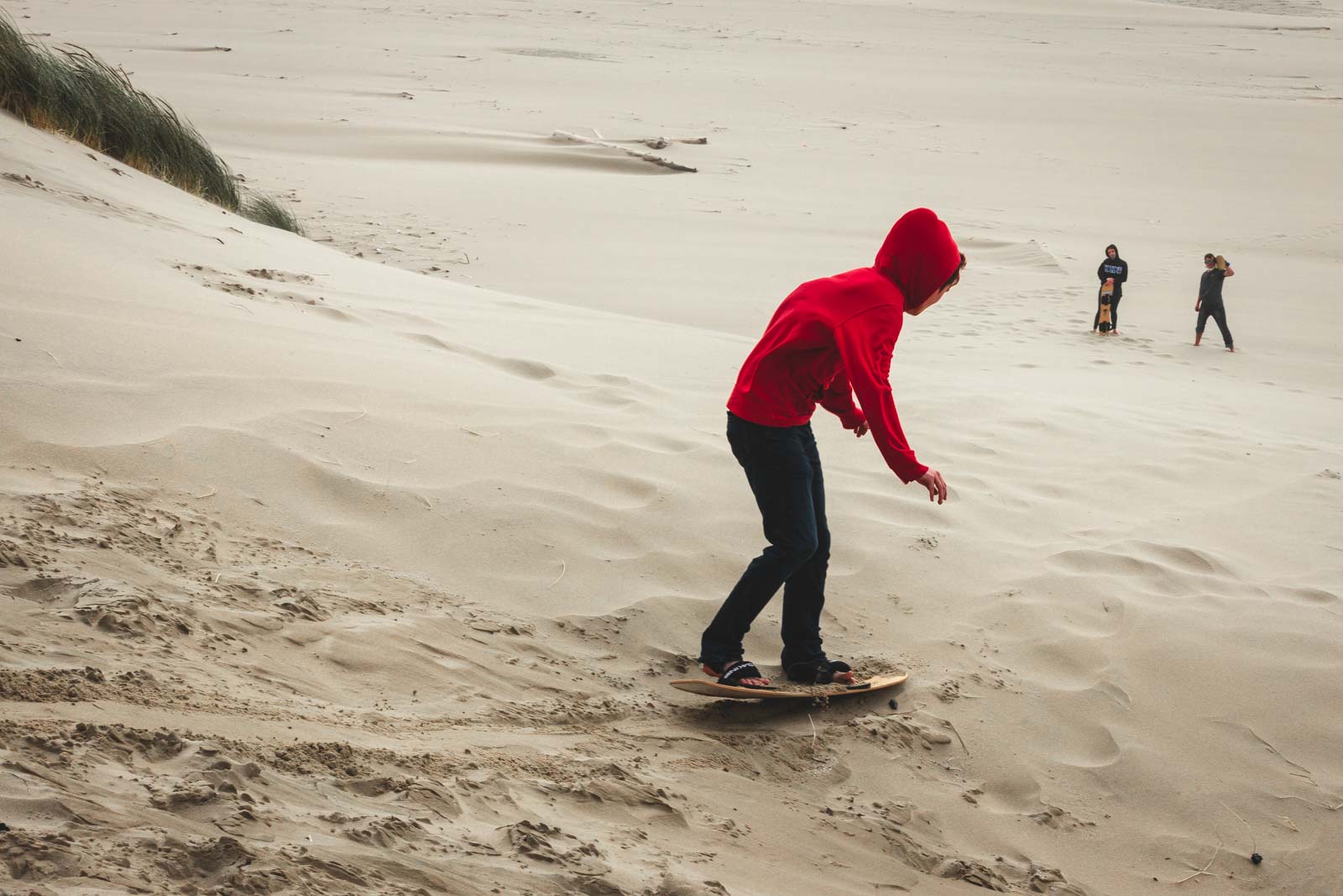 Boy in red enjoying sandboarding at Oregon Dunes.