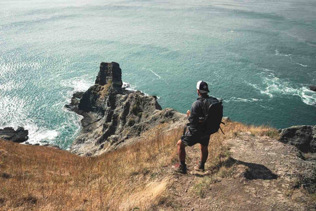 Hiker looking out over the sea and rocks from Cape Falcon