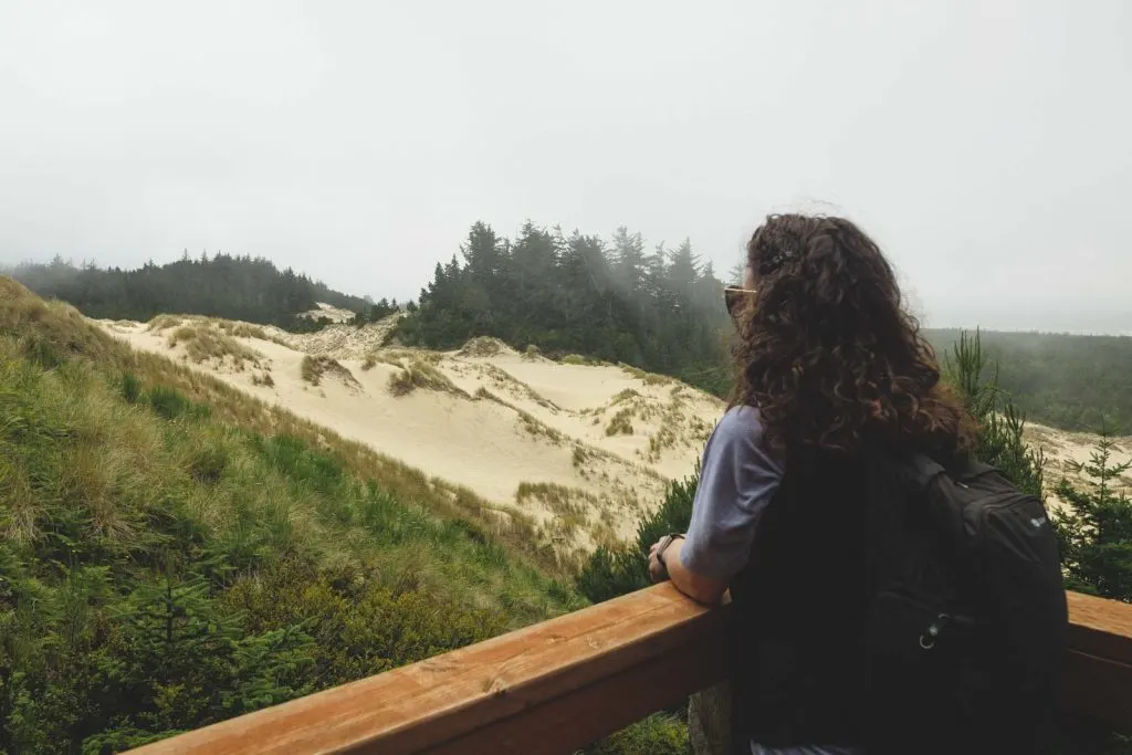 Nina looking out over sand dunes at Oregon Dunes National Recreational Area on the Oregon Coast