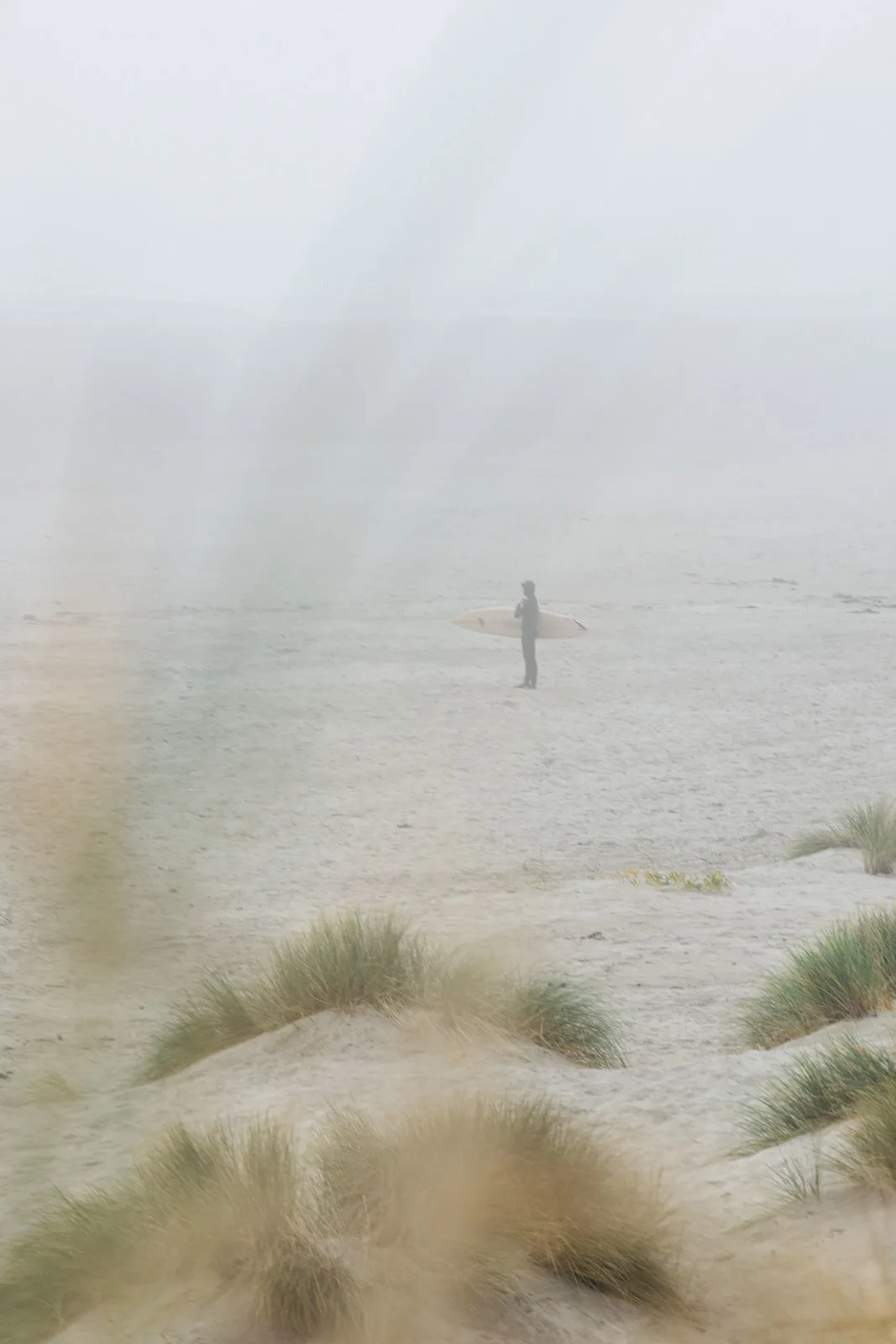 Surfer standing on beach in fog at South Beach State Park in Oregon