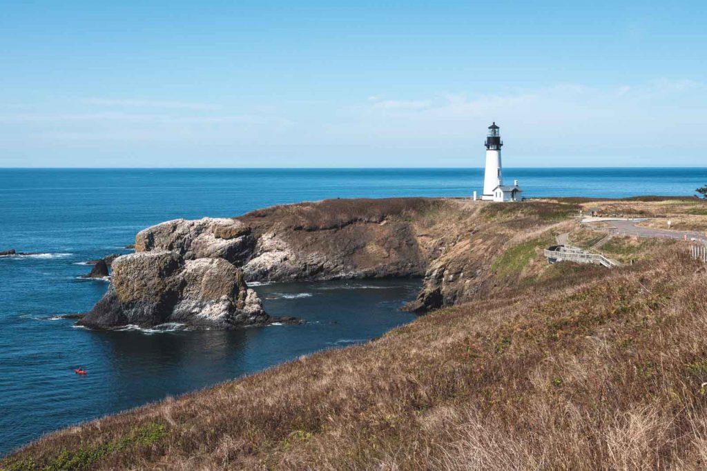 View of Yaquina Head Lighthouse on peninsula with ocean in the background.