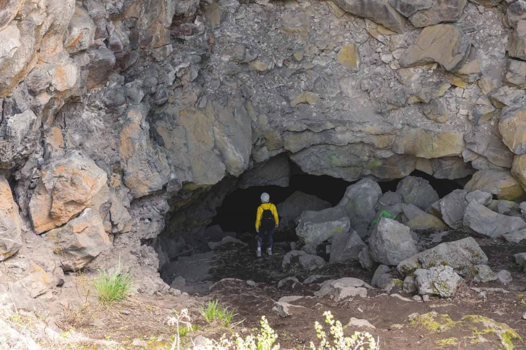 Person entering mouth of Arnold Ice Cave near Newberry National Volcanic Monument in Oregon
