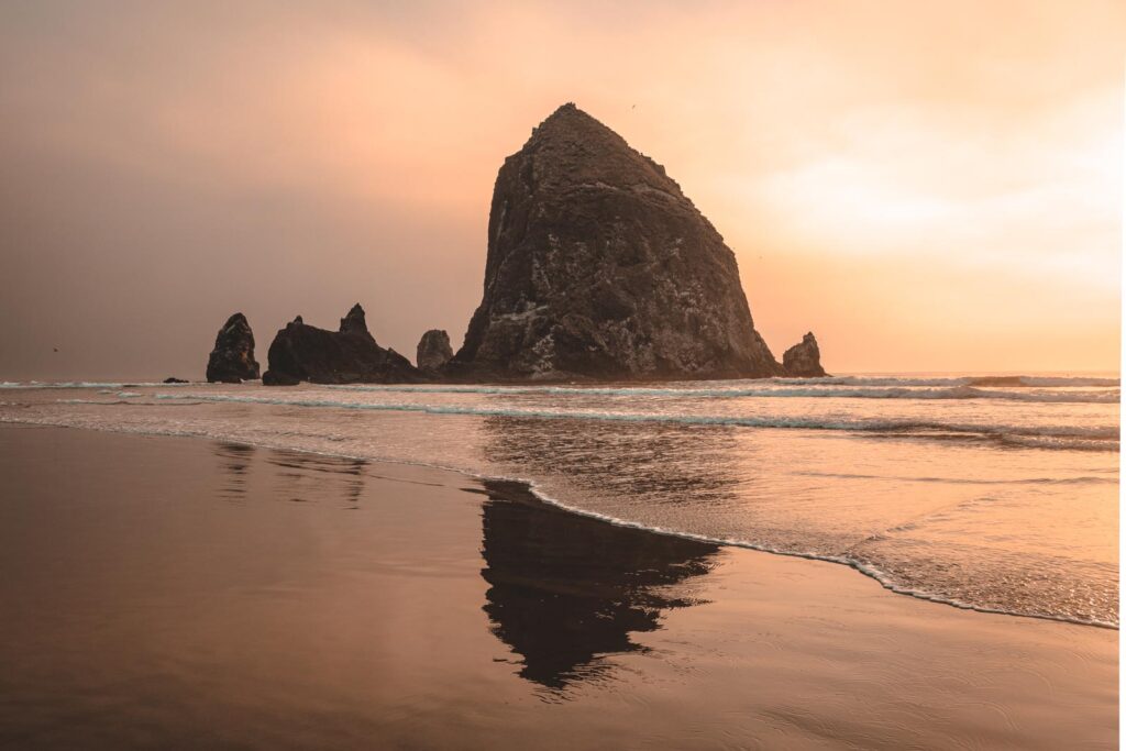 Haystack Rock reflecting on wet beach at Cannon Beach, one of the best beaches on the Oregon Coast