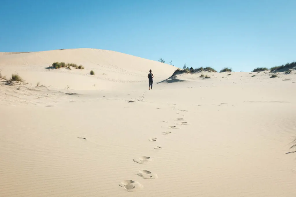 Person hiking in sand dunes to John Dellenback trails beach, one of the best beaches in Oregon