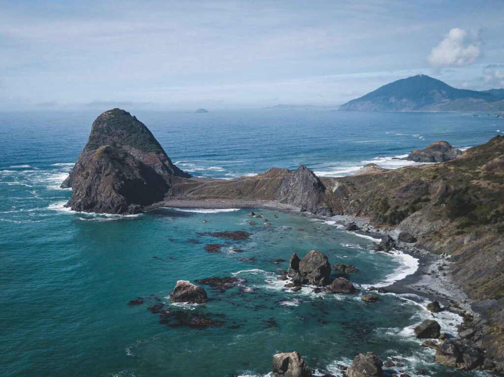 Aerial view over rocky islands and peninsula and ocean at Sisters Rock State Park, home to one of the best beaches in Oregon