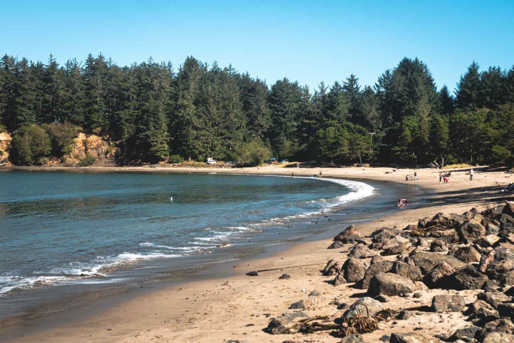 Sandy cove beach with forest in background at Sunset Bay State Park, home to one of the best beaches in Oregon