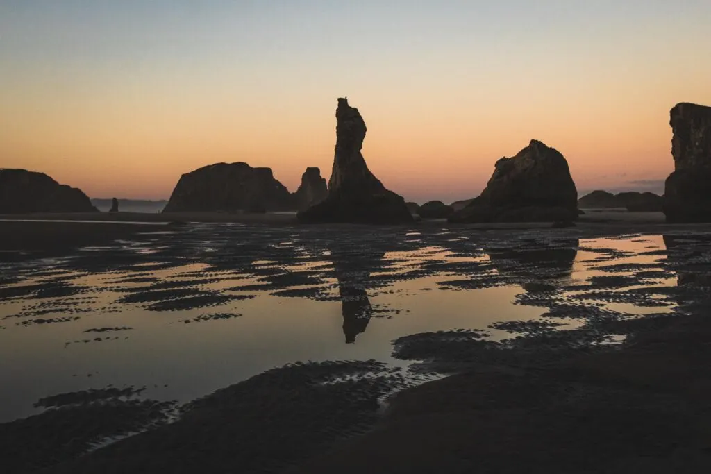 Rock formations with water in foreground at sunset at Bandon Beach in Oregon