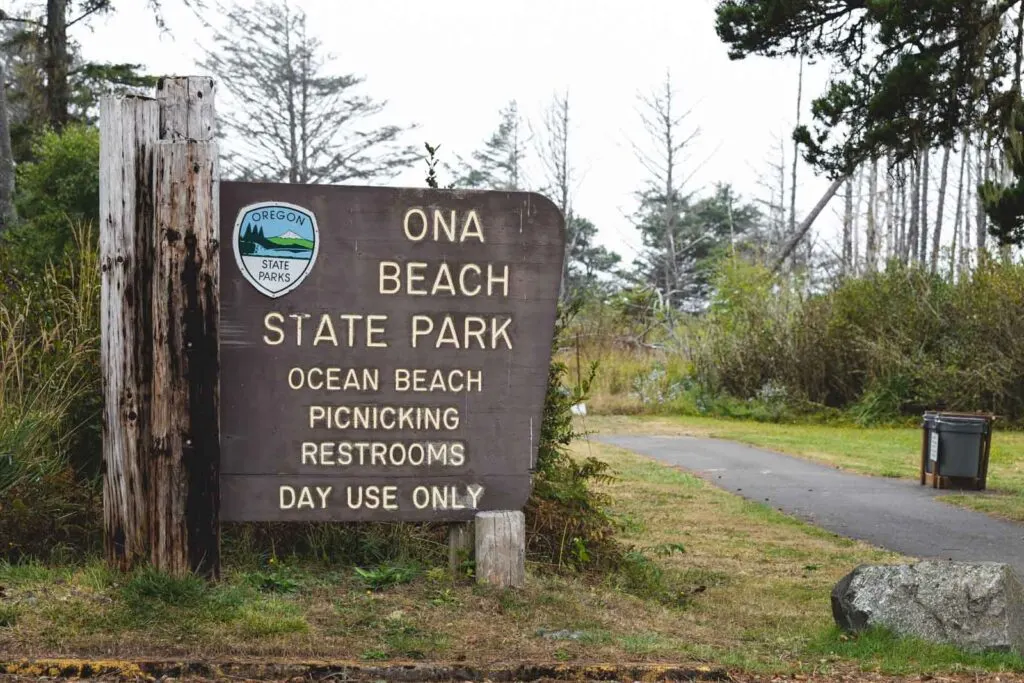 Entrance sign with road beside it to Ona Beach State Park - one of the best things to do in Newport Oregon