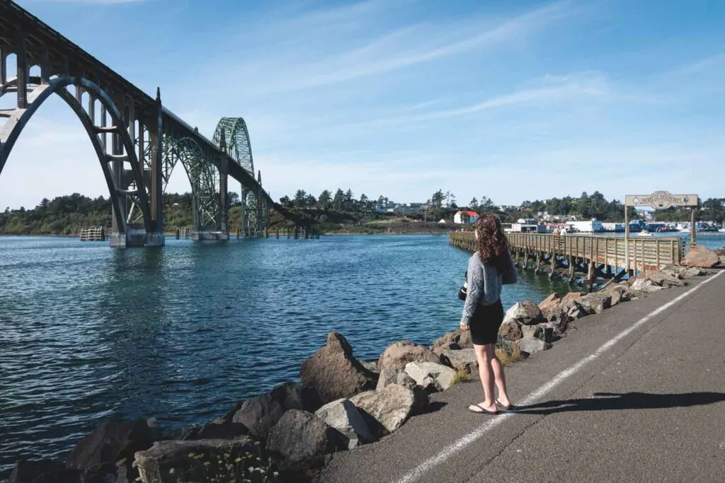 Woman standing on path and looking over to bridge in Newport, Oregon
