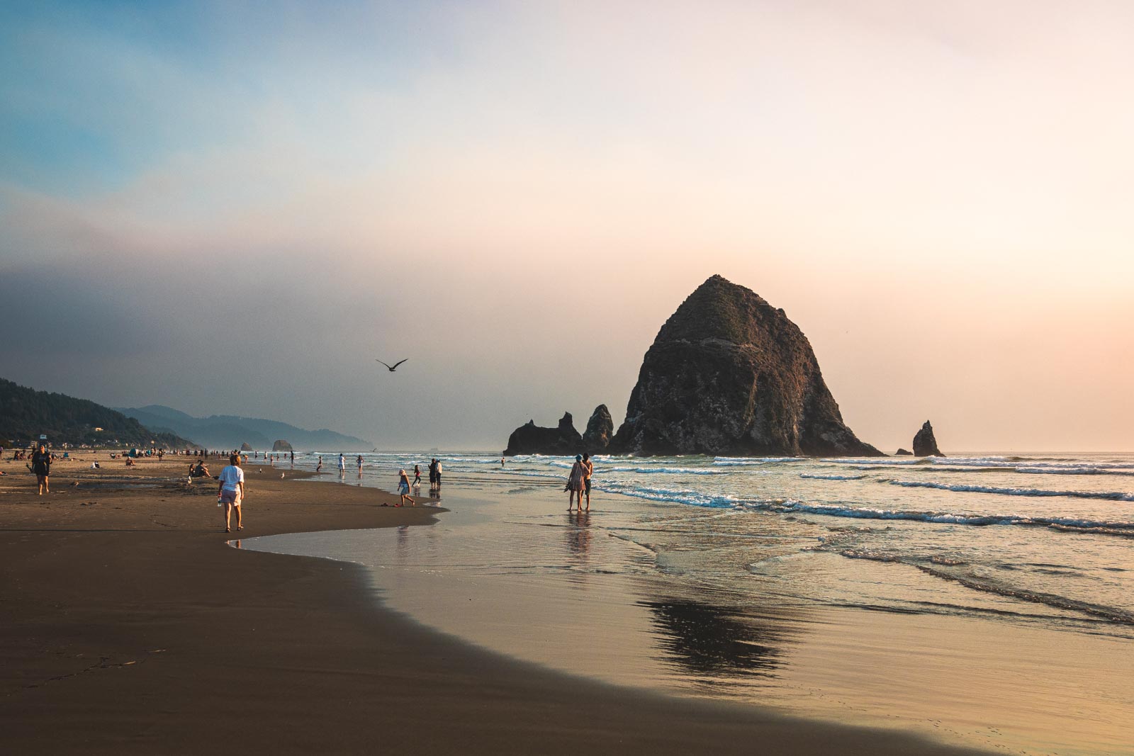 People walking on Cannon Beach with Haystack Rock, one of the best things to do in Seaside Oregon