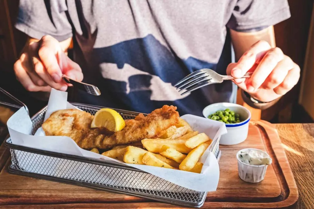 Person eating fish and chips - sampling the food scene is one of the best things to do in Seaside
