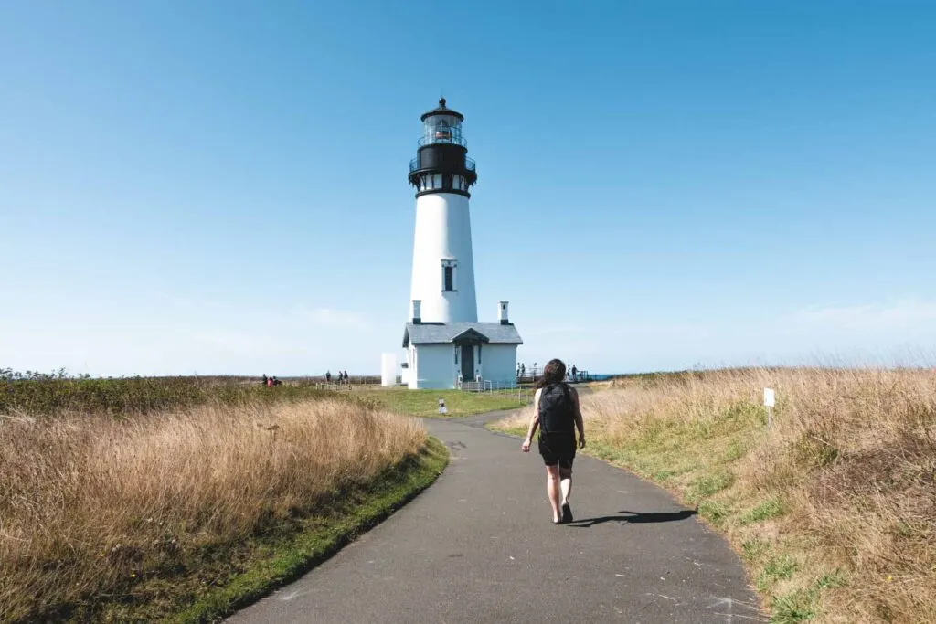 Woman walking path to Yaquina Head Lighthouse in Newport, Oregon