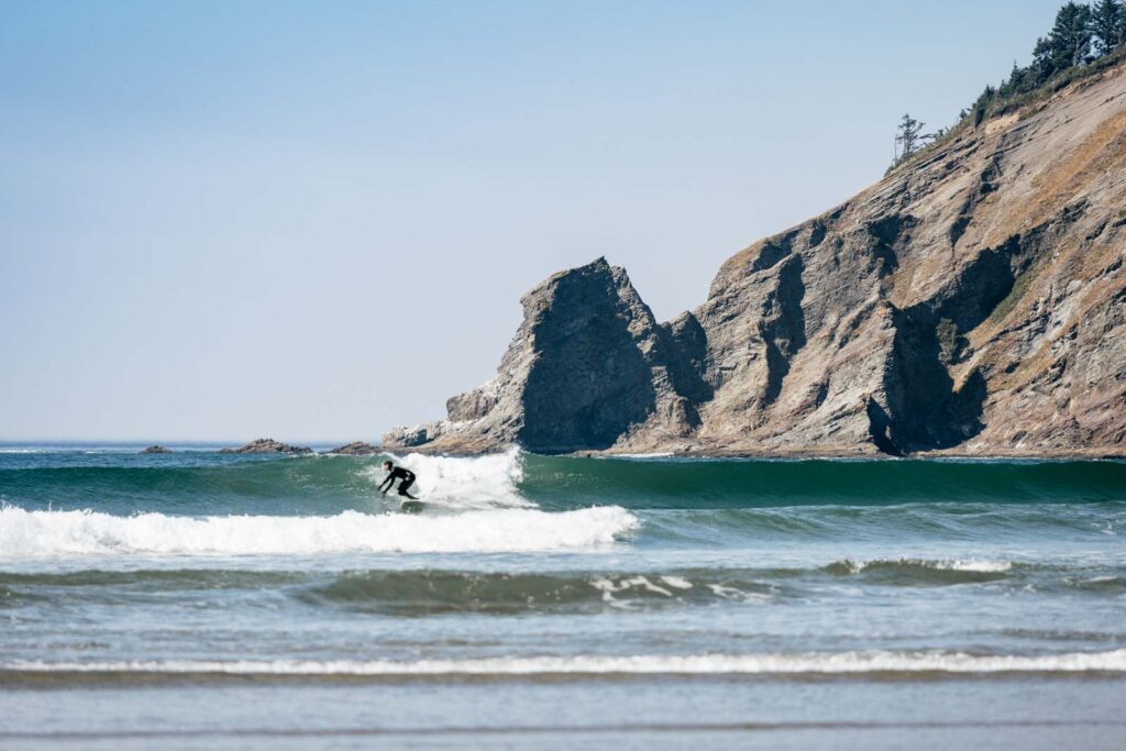 Surfer ripping a wave besides a cliff face at Short Sand Beach in Oswald West State Park.