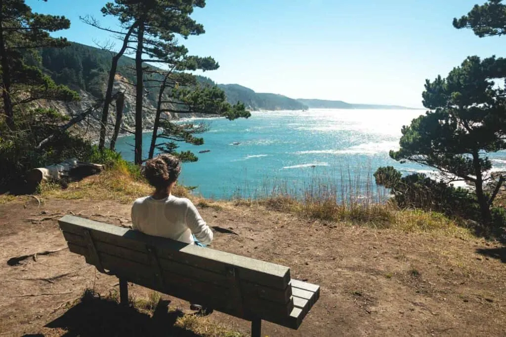Woman sitting on bench and looking out to sea at Cape Arago