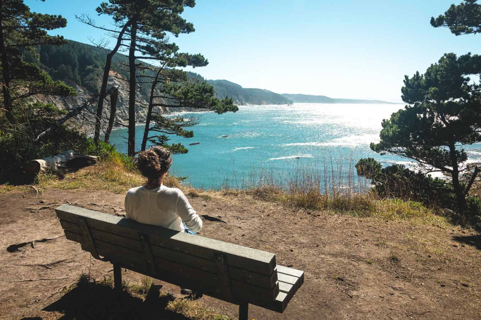 Woman sitting on bench and looking out to sea at Cape Arago.