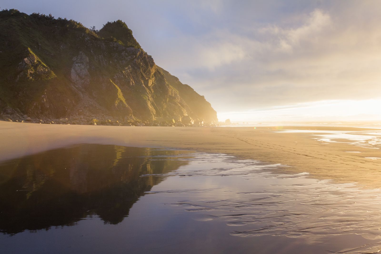 Cape Sebastian at sunset with the mountains in the distance reflecting off the water below.