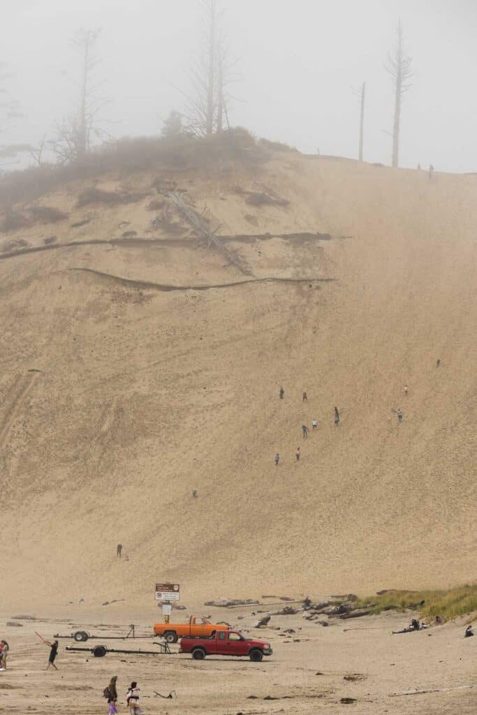 Giant sand dune in the fog with people climbing it at Cape Kiwanda