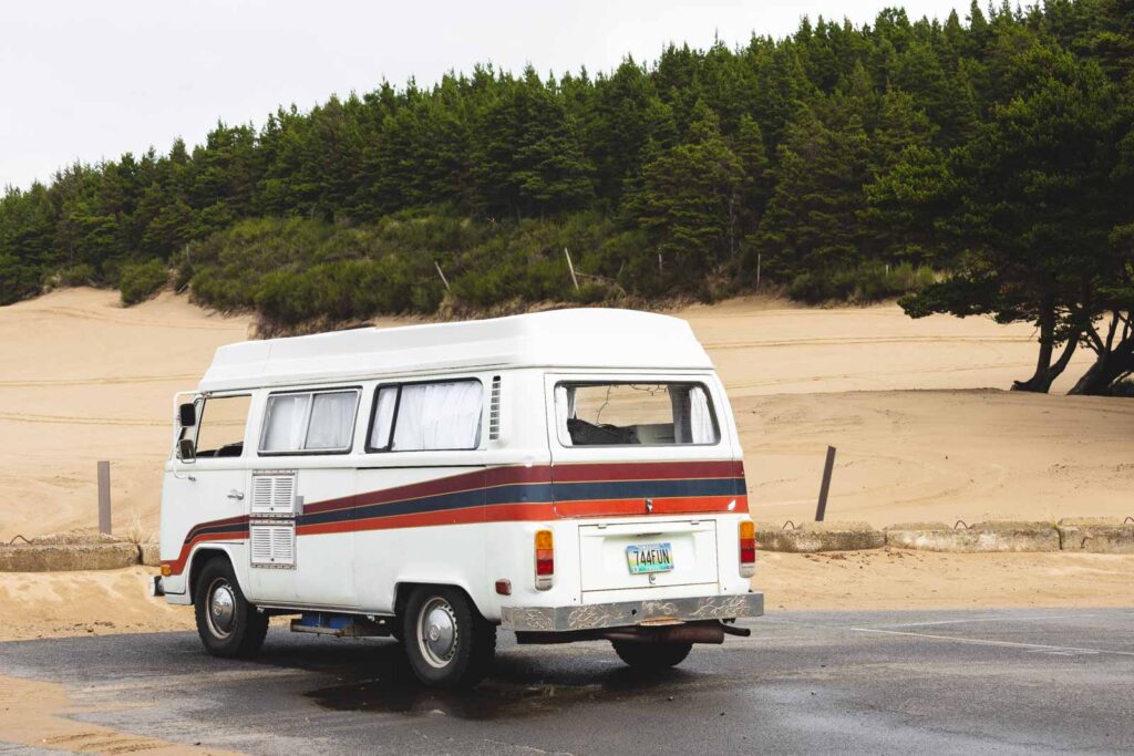 VW van parked in carpark with trees and sand in background at Sand Lake near Pacific City