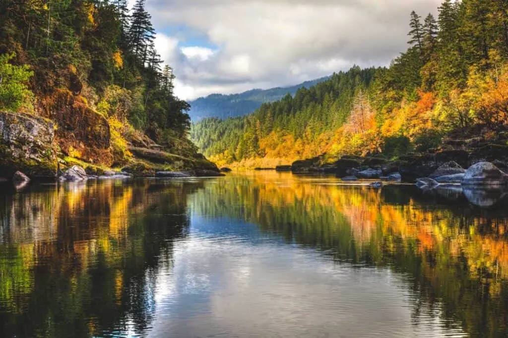 A rainbow of fall colors is reflected in the smooth Rogue River near Gold Beach