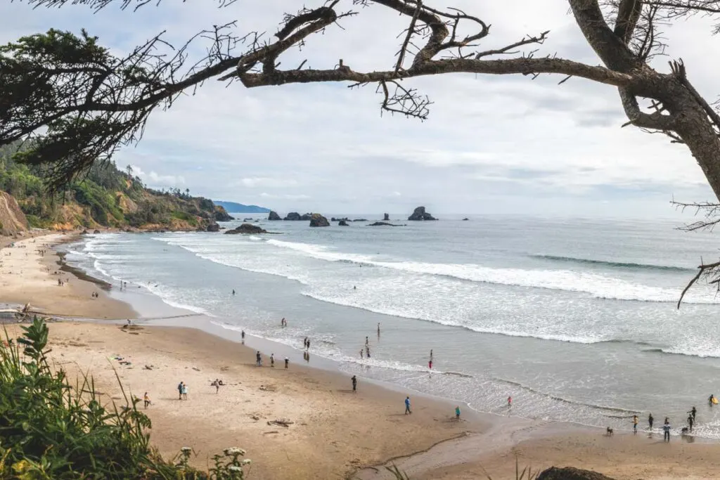 Indian Beach in Oregon. View of Indian Beach with people on the sand and in the water with rocky islands. Near Tillamook Rock Lighthouse.