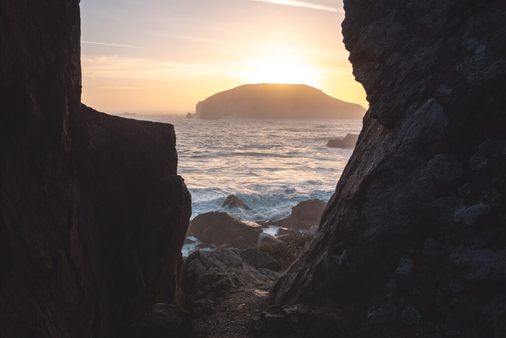 View of the sunset over the sea between rocks in harris state beach park