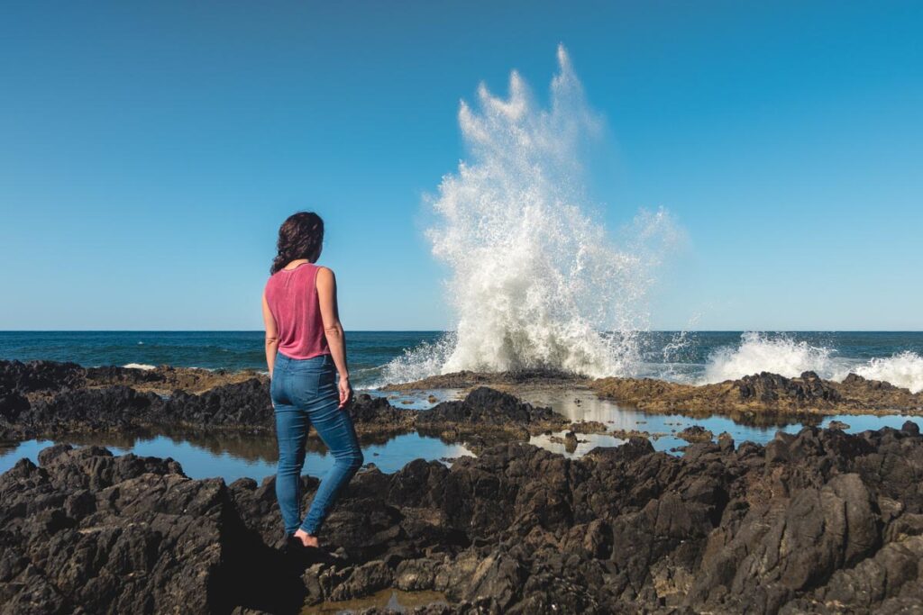 Woman watching waves crash at Devil's Churn in Cape Perpetua