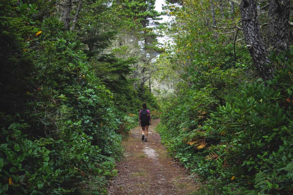 Woman hiking through trees on the Blacklock Point Trail