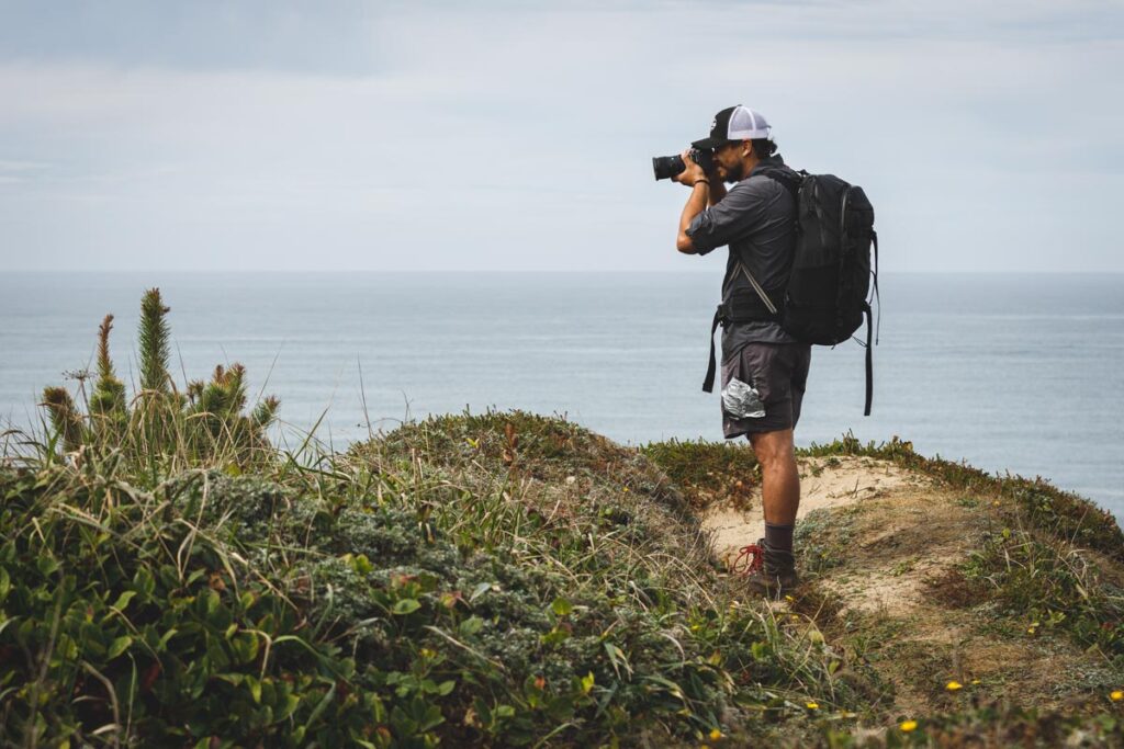 Man taking photos on cliff at Floras Lake, Oregon