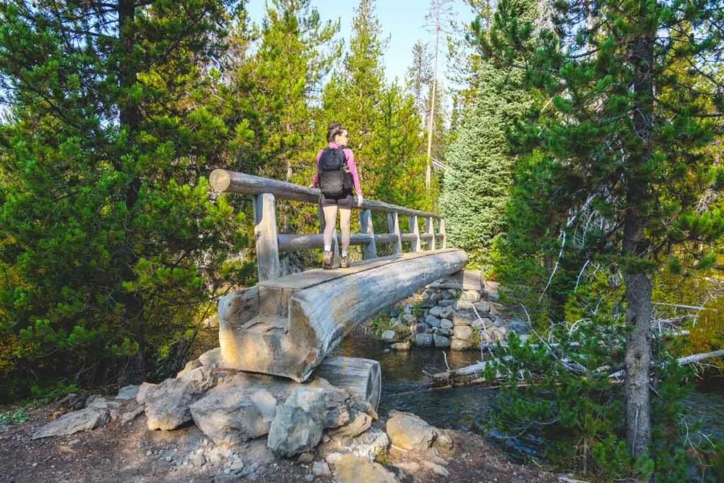 Hiker crossing wooden bridge on the Green Lakes Route of the Moraine Lake Trail