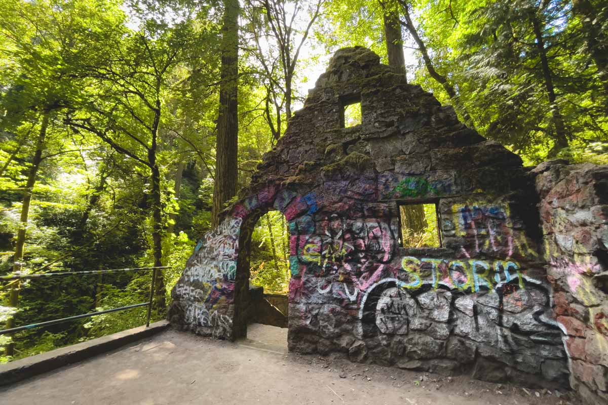 Witch's Castle in Forest Park covered in graffiti with trees behind it.