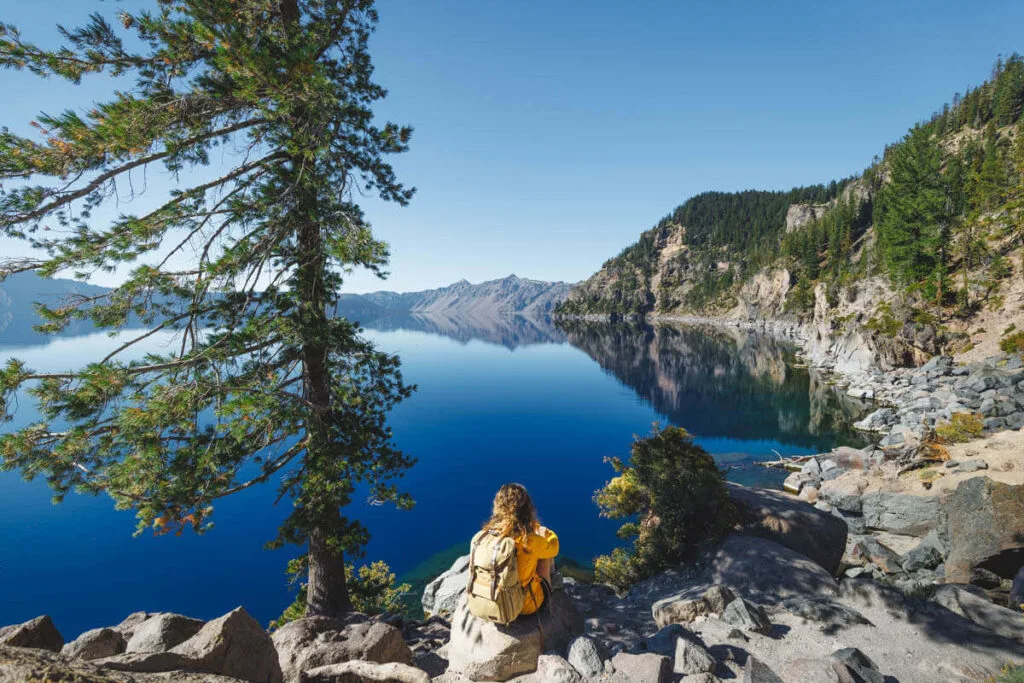 Hiker sitting by Crater Lake on the Cleetwood Cove Trail