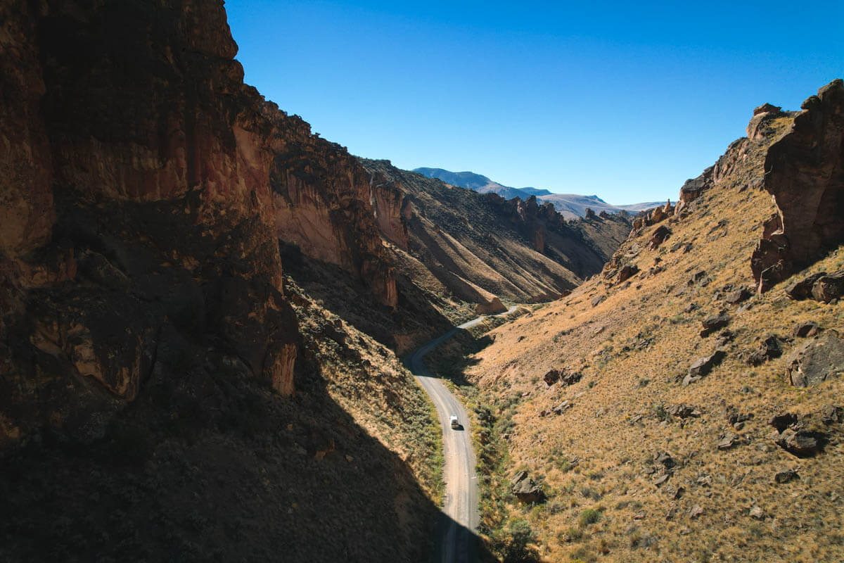 Aerial view of a campervan driving through the huge cliffs of Leslie Gulch.