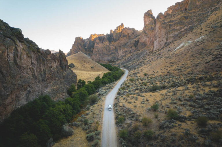 A campervan driving along a dirt track through Succor Creek at golden hour.