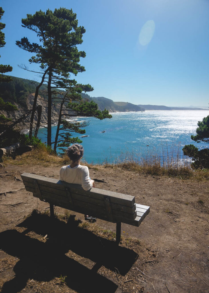 A woman relaxing on a beach looking out to sea on the South Cove Trail in Cape Arago State Park.