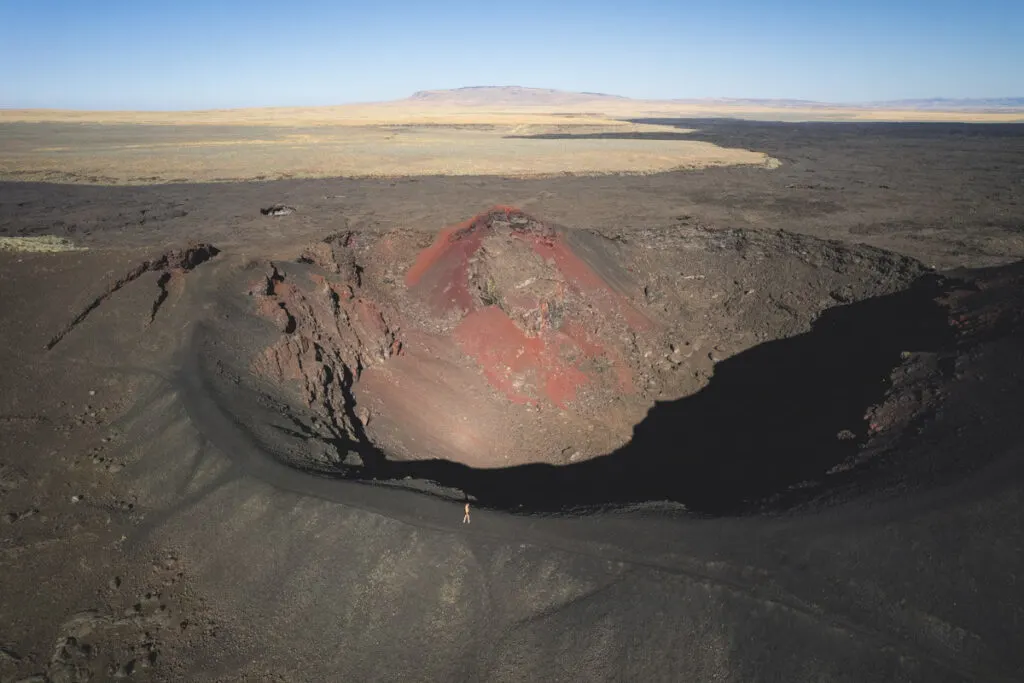 An aerial view of a woman walking around the rim of a huge crater in Jordan Valley, Oregon.
