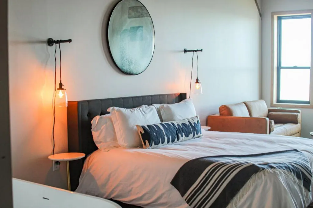 Warm tungsten lights illuminate the bright white double bedroom of the Bowline Hotel in Astoria.