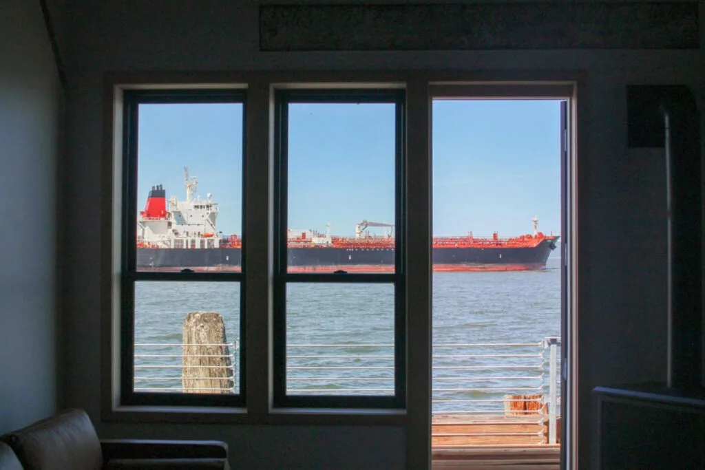 A cargo ship passing by the Bowline Hotel, seen through a window of the hotel.