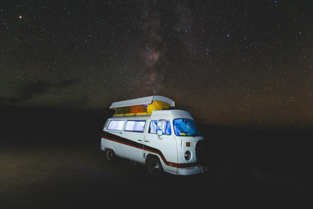 A white campervan under a sky full of stars in Fish Lake Recreation Site.