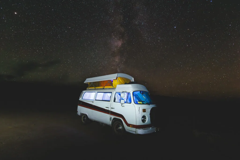 A white campervan under a sky full of stars in Fish Lake Recreation Site.