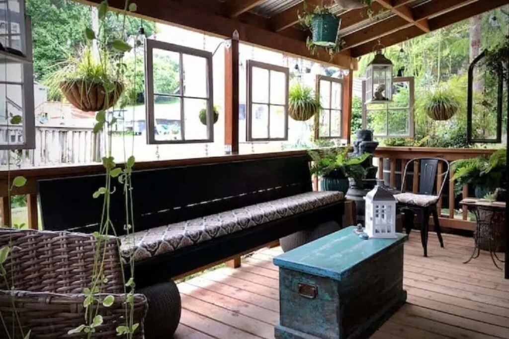 A patio with a long outdoor bench and many plants Downtown Astoria Tiny House.