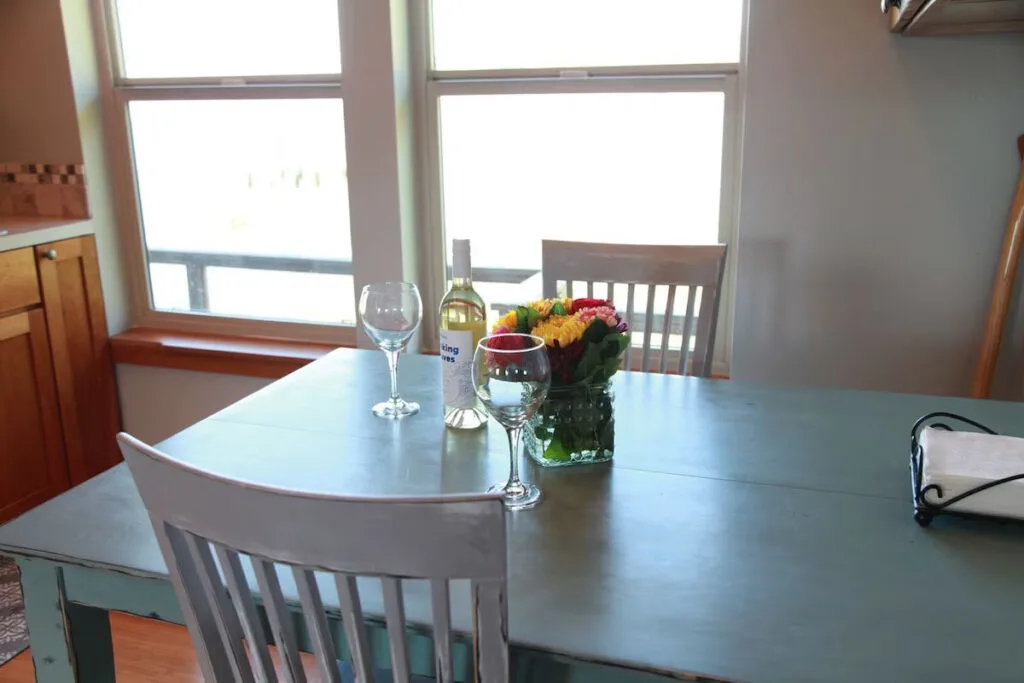 A vase of colorful flowers, a bottle of white wine and some wine glasses on the table in the kitchen of the Historic Astoria Home.