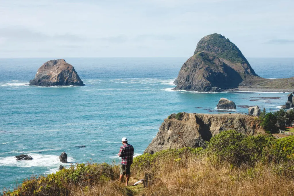 A man standing by a cliff flying a drone over Sisters Rock State Park. A man standing by a cliff flying a drone over Sisters Rock State Park.