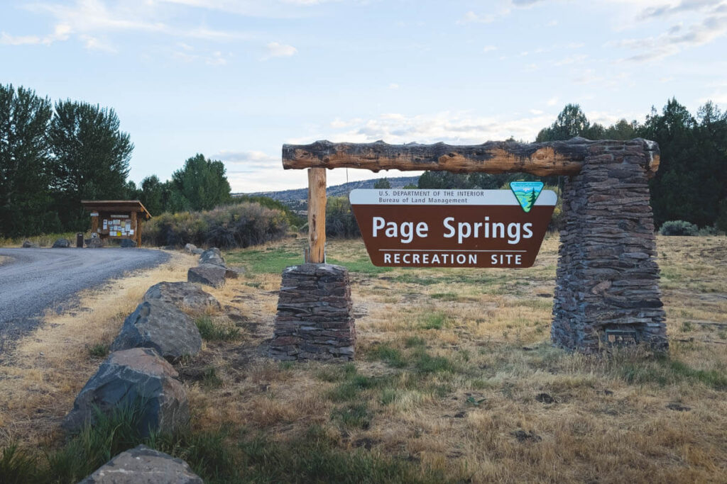 The Page Springs Recreation Site entryway sign next to a gravel road.