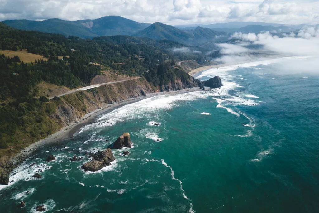 An aerial view of a layer of clouds encroaching on Sisters Rock Beach in Oregon.