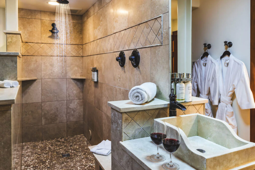 The beautiful bathroom area with red wine and robes at The Inn at Arch Cape.