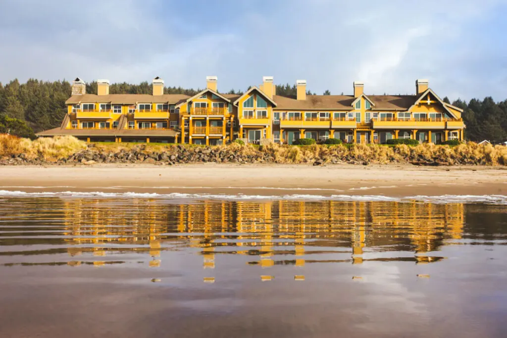 The Ocean Lodge accommodation from the outside reflected in the wet Cannon Beach sand in front of the property.